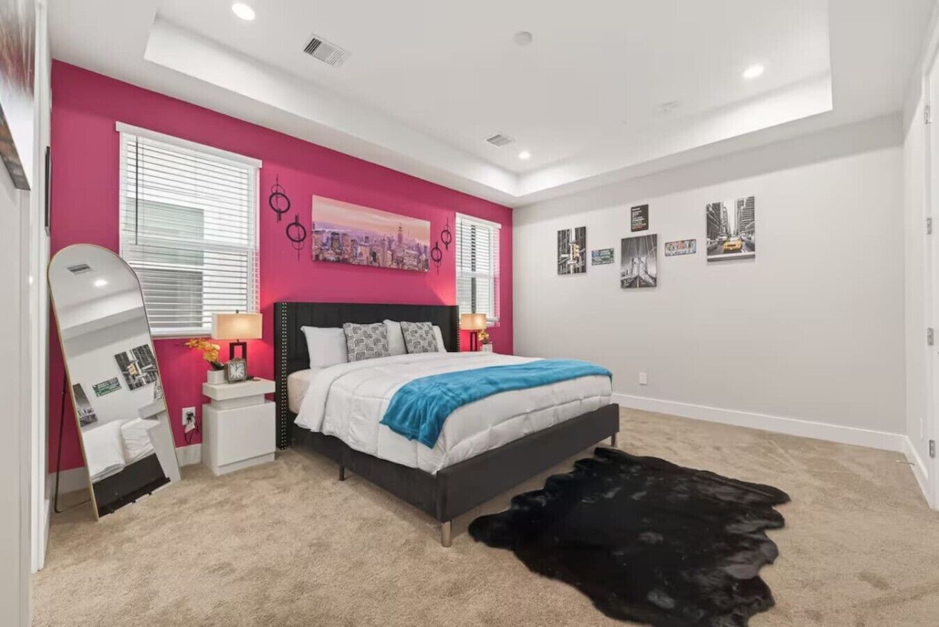 Un dormitorio con cama, mesitas de noche, un espejo y decoración en la pared.