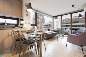 A modern apartment with a dining area, kitchen, and seating space with a view of the city. - Excellent Location in Las Condes | Just Steps from the Manquehue Metro Station (Las Condes)