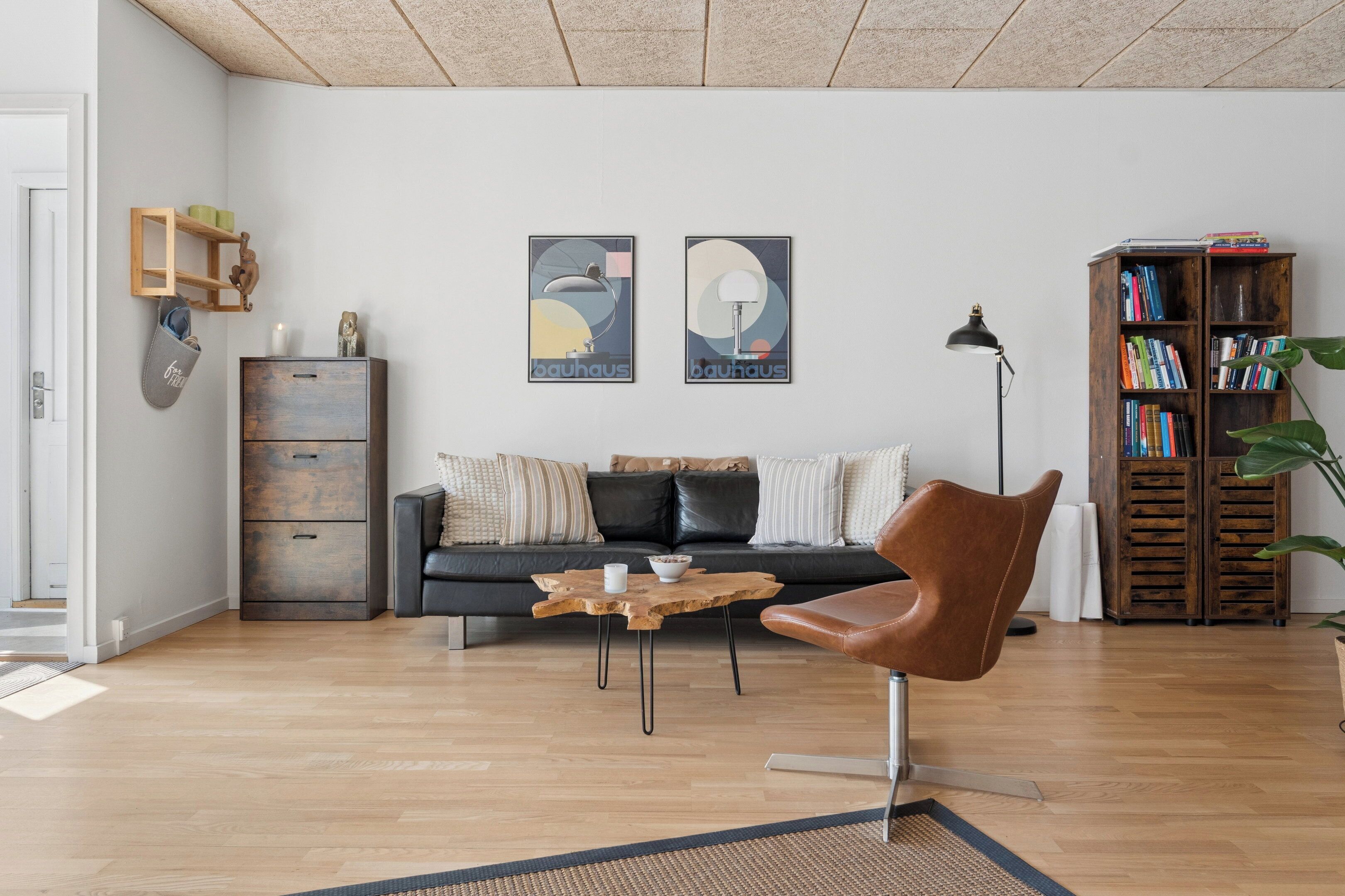 A modern living room with a leather sofa, a wooden coffee table, and a bookshelf.