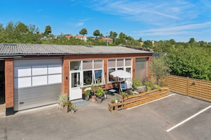 A single-story building with a garage, a patio with seating, and a view of a residential area.