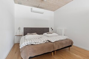 A bedroom with a bed, a bedside table, a lamp, and a radiator.