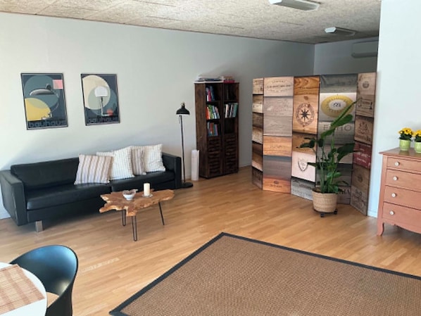 A living room with a black sofa, a coffee table, a bookshelf, and a decorative wall panel.