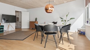 Un comedor moderno con una mesa redonda, sillas negras y una lámpara colgante.