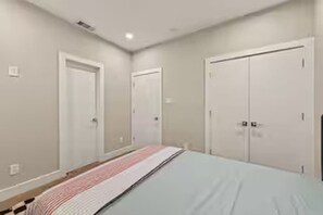 A bedroom with a bed, two doors, and a light switch on the wall. - Sleek New Retreat in Up-and-Coming Houston (Houston)