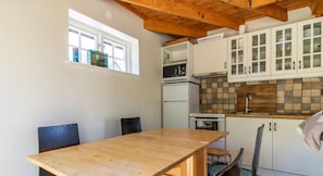 A compact kitchen with a wooden table, cabinets, a microwave, a refrigerator, and a window. - Holiday home on the beautiful island of Aspö (Drottningskär)