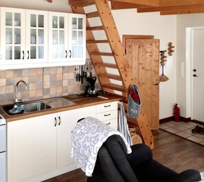 A kitchen with a sink, cabinets, and a coffee maker. There is a wooden staircase and a door with a coat hanging on it. - Holiday home on the beautiful island of Aspö (Drottningskär)