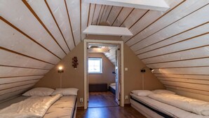Ein kleines Schlafzimmer im Dachgeschoss mit zwei Betten, einem Fenster und einer schrägen Decke.
