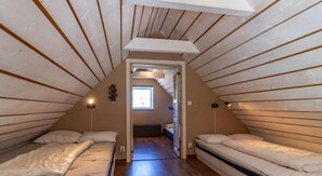 A small attic bedroom with two beds, a window, and a sloped ceiling. - Holiday home on the beautiful island of Aspö (Drottningskär)
