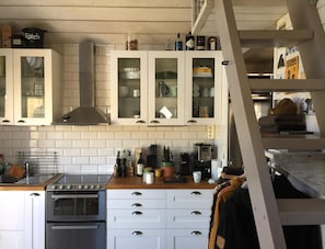 A kitchen with white cabinets, a stove, and various kitchen items.