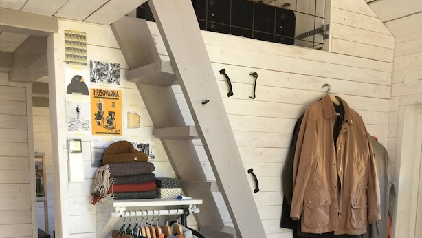 A clothing rack with various garments and a pair of shoes.