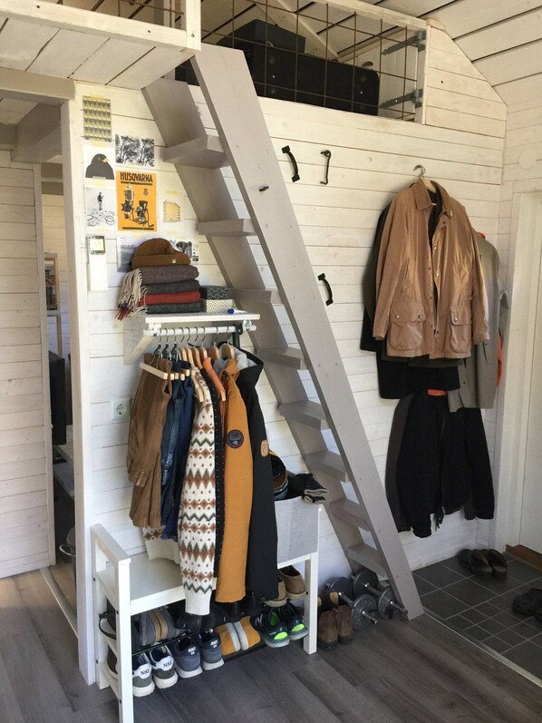 A clothing rack with various garments and a pair of shoes.