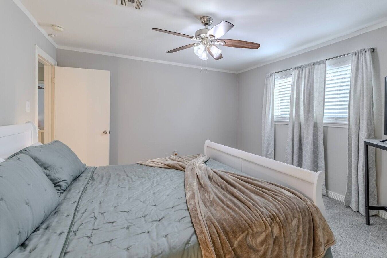Ein Schlafzimmer mit zwei Betten, einem Deckenventilator, einem Fenster mit Vorhängen und einem Fernsehschrank.