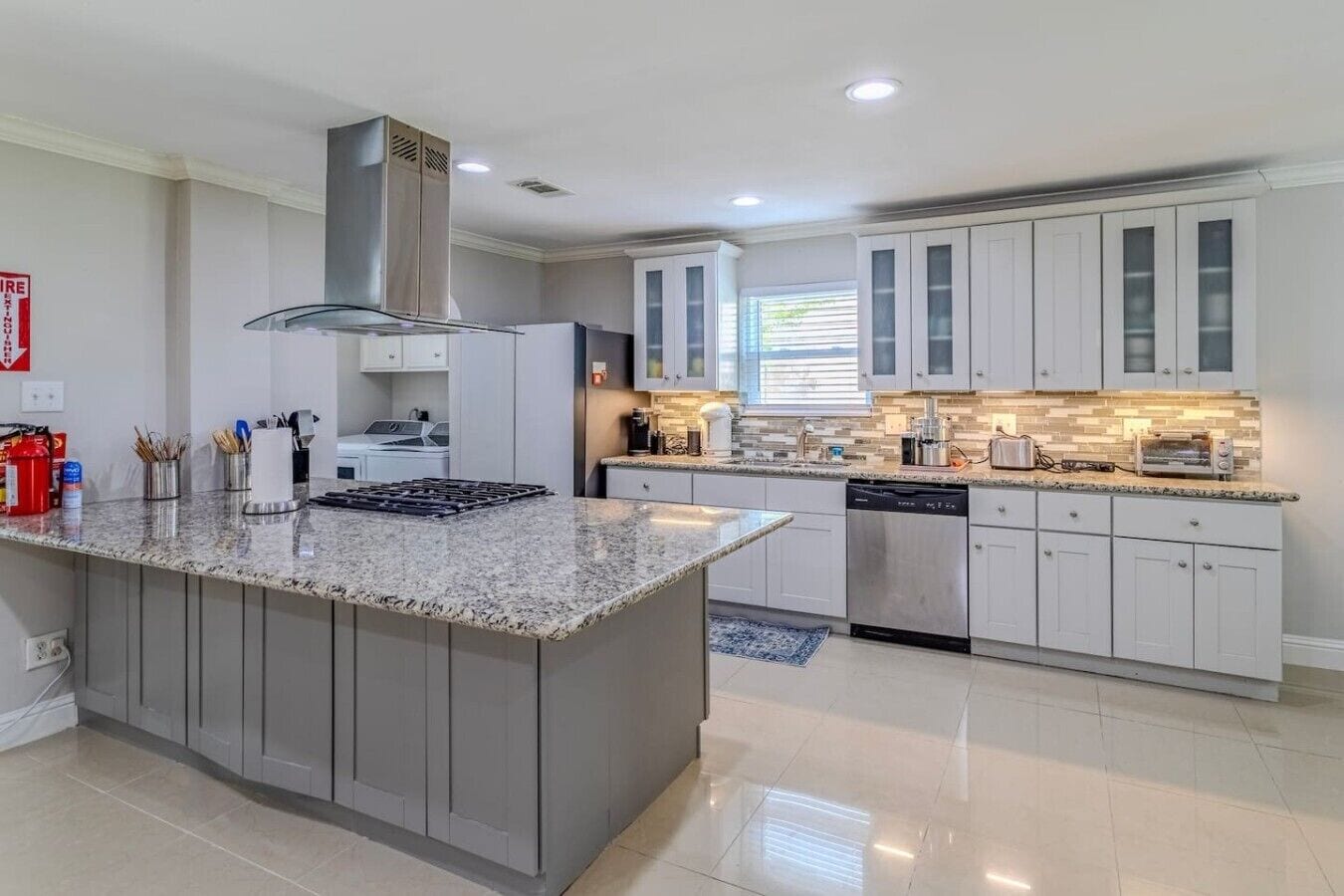 Una cocina moderna con una isla central, electrodomésticos integrados y un amplio ventanal que proporciona luz natural.