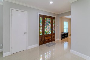A hallway with a white door, a wooden door with stained glass, and a bench. - Energy Corridor 4BR | Near I-10 & Hwy 6 (Houston)
