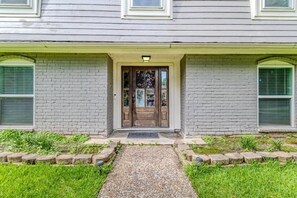 A two-story building with a front door, a small porch, and a gravel pathway leading to the entrance. - Energy Corridor 4BR | Near I-10 & Hwy 6 (Houston)