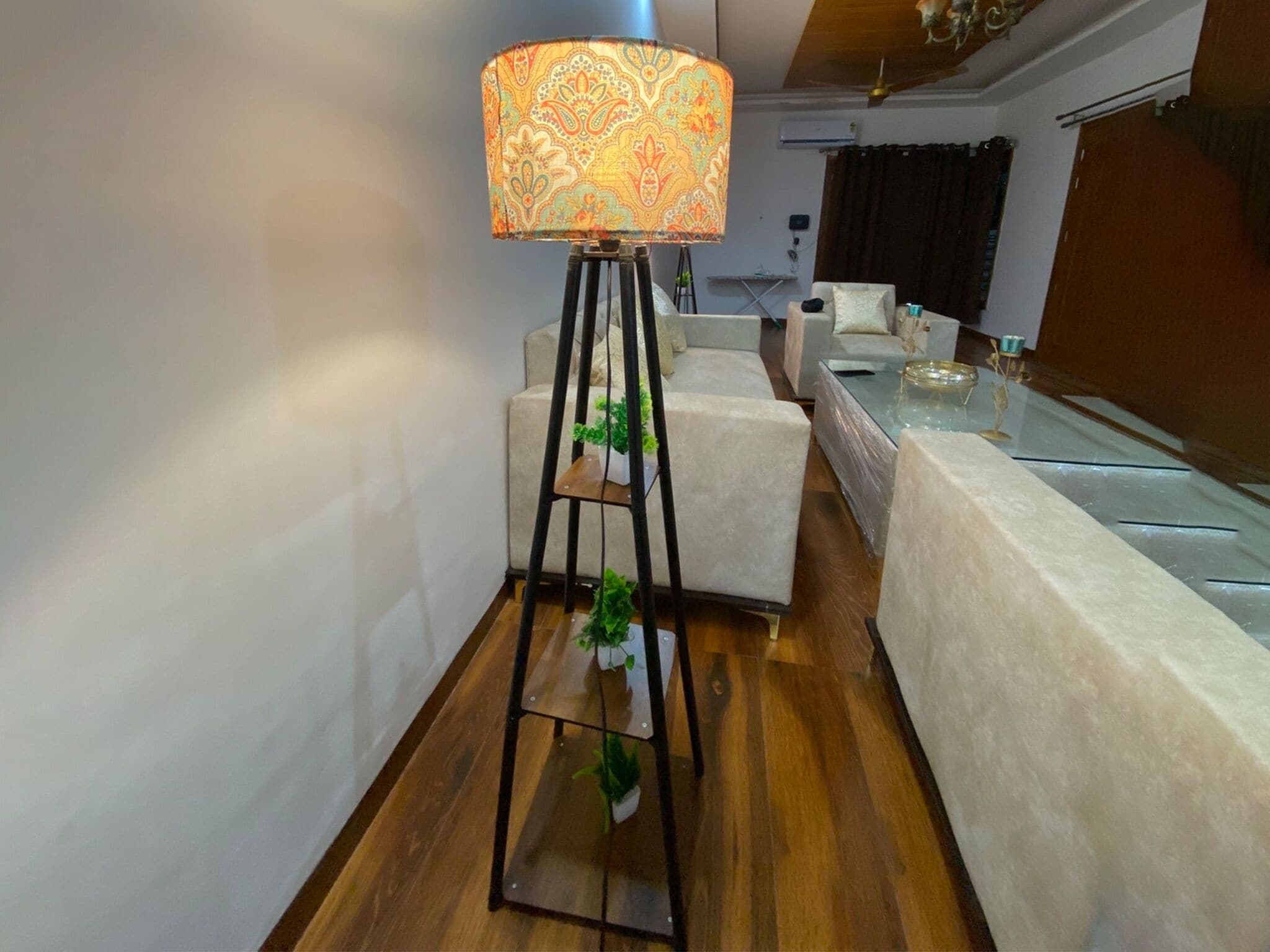 A modern living room with a standing floor lamp, a sofa, a coffee table, and a small plant.