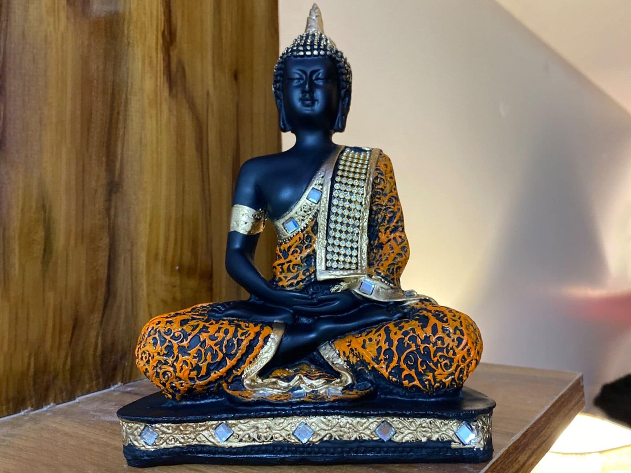 A statue of a seated figure with intricate patterns on the robe, placed on a pedestal.