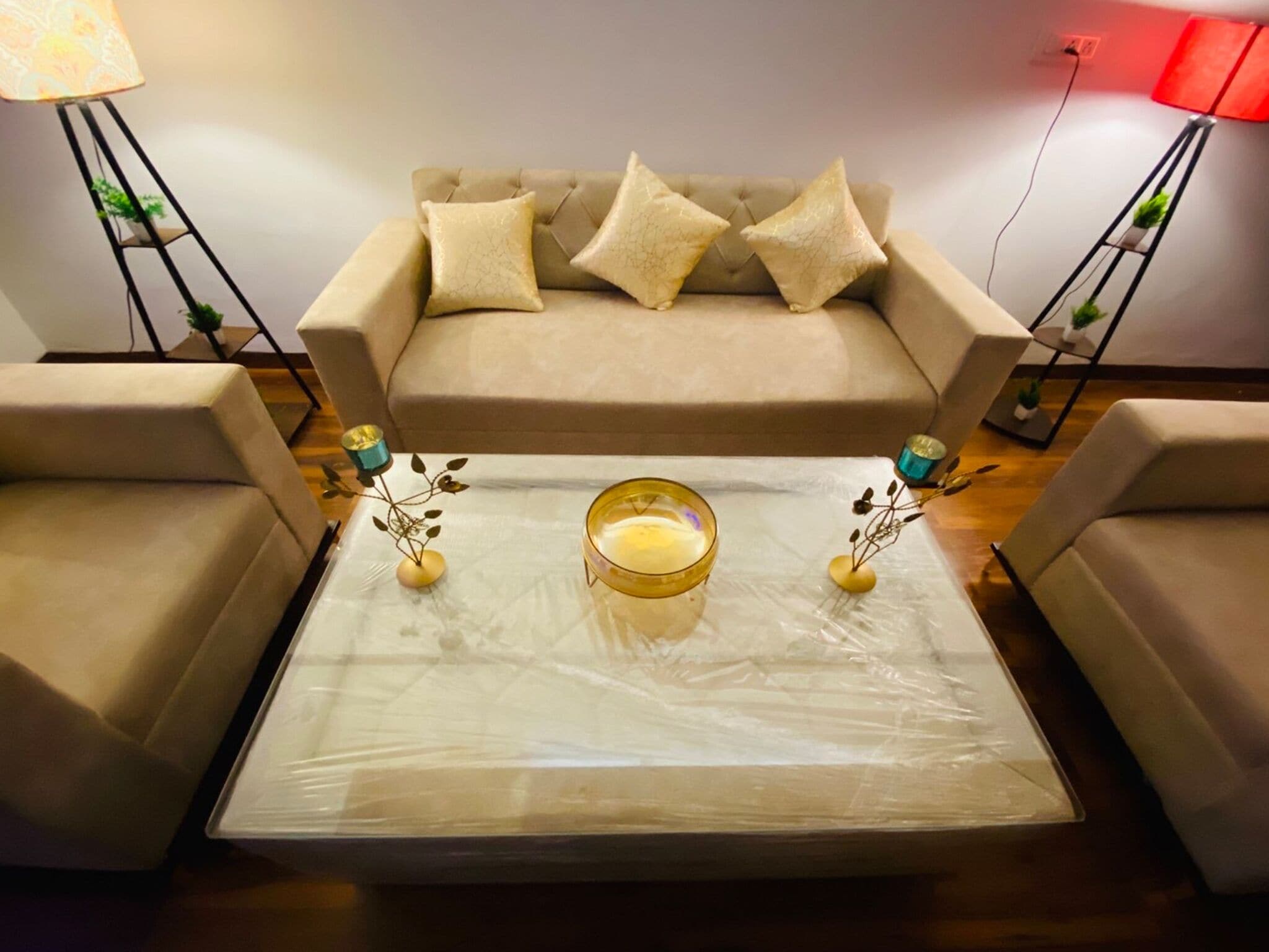 A living room with a sofa, two armchairs, a coffee table with decorative items, and lamps on either side.