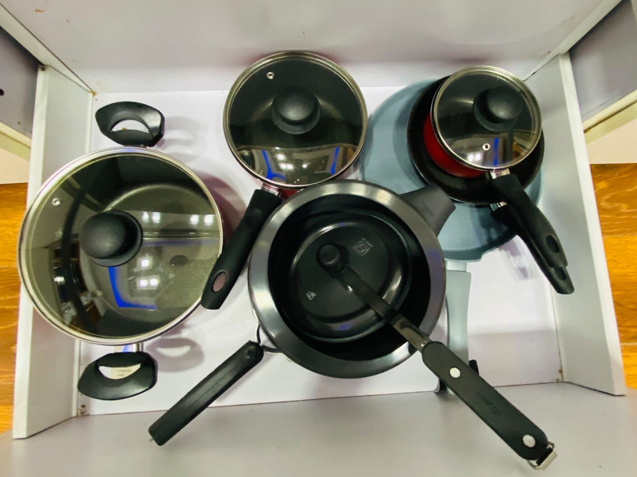 A kitchen with a stove, a pot, a pan, and a kettle.