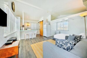 A modern living room with a grey sofa, a small coffee table, and a TV on a wooden stand. - Beach Break by Coastline Vacation Rentals (San Diego)