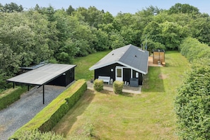 A single-story house with a sloped roof, a small porch, and a fenced yard. - Holiday Home in Jegum Ferieland (Oksbøl)
