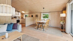 En ombonad inredning med en matplats, ett kök och ett vardagsrum med en soffa och ett bord.