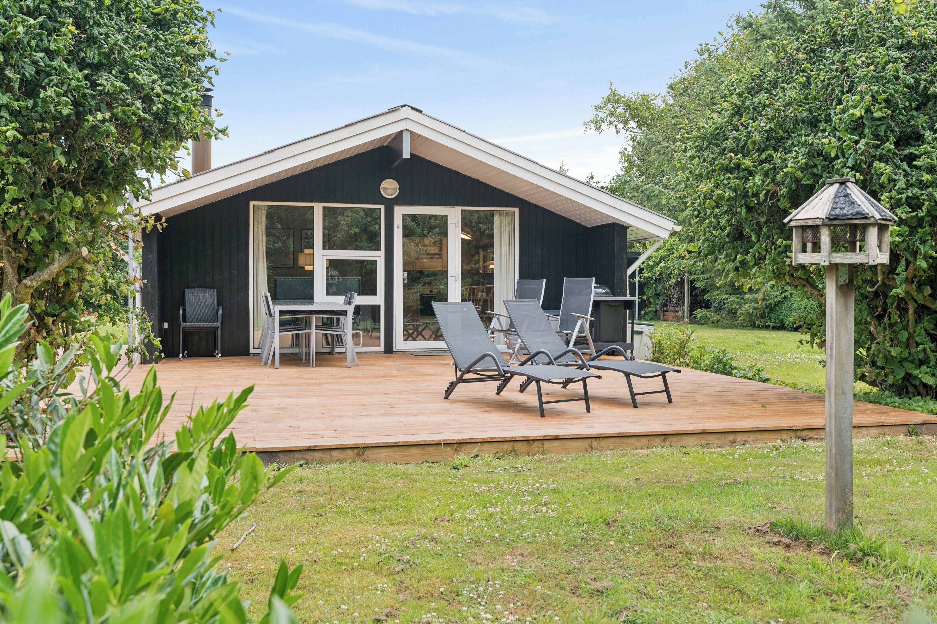 Une maison avec une terrasse, un espace salon extérieur et une mangeoire à oiseaux.