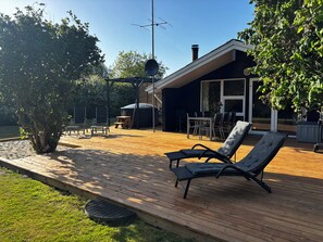 A deck with lounge chairs, a barbecue area, and a patio table. - Holiday Home in Jegum Ferieland (Oksbøl)