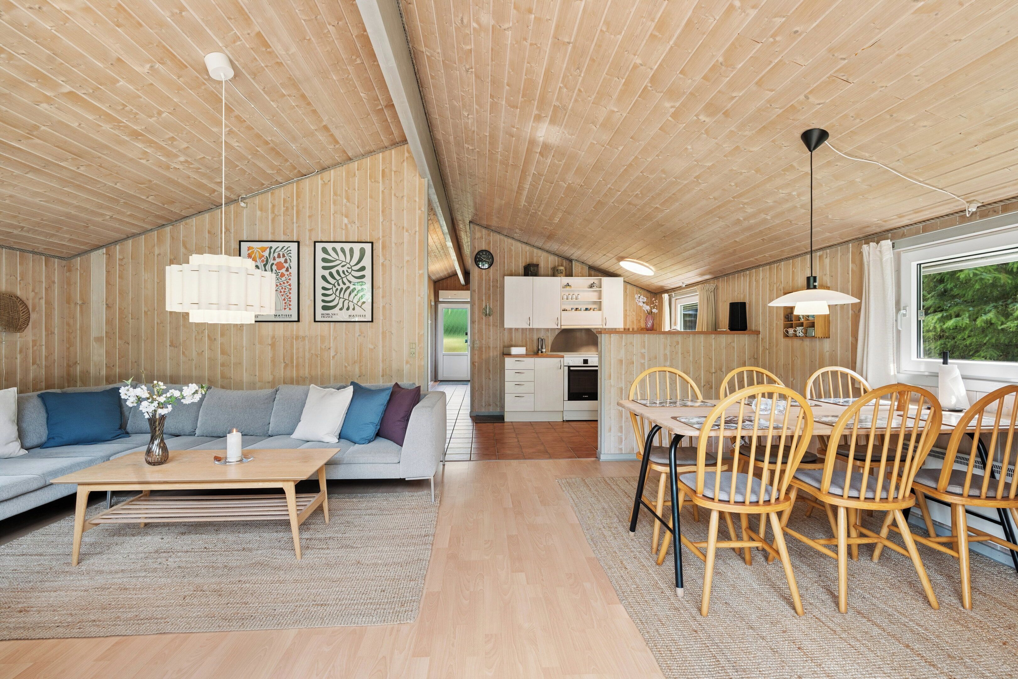 Ein gemütliches Cabin-Interieur mit einer Couch, einem Esstisch, Stühlen und Kunstwerken an den Wänden.