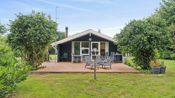 Ett hus med en veranda, utomhusmöbler och en skorsten.