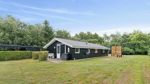 En envåningsbyggnad med en mörk fasad, ett sluttande tak och en liten veranda.
