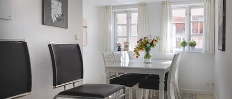 A dining area with a table, chairs, and a vase of flowers.