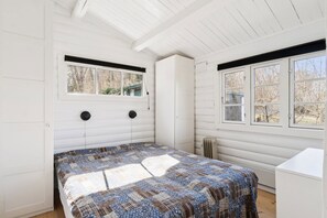 A bedroom with a bed, two windows, a radiator, and a white dresser. - Authentic holiday home with Baltic Sea view (Allinge-Sandvig)