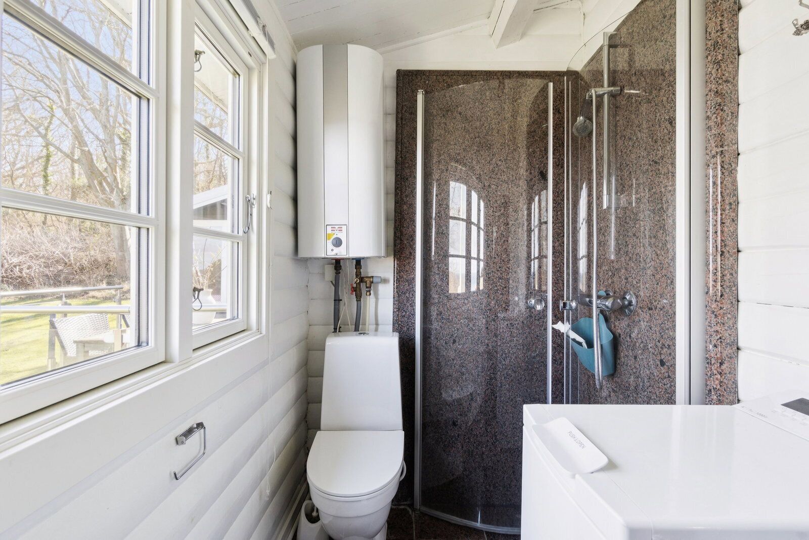 Un baño con inodoro, cabina de ducha y ventana.