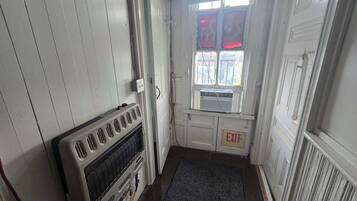 Un couloir étroit avec un radiateur, un panneau indiquant la sortie et une fenêtre dotée de vitres teintées en rouge.