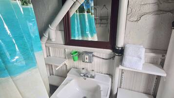 Une salle de bain comprenant un lavabo, un miroir, un porte-serviettes et un espace douche.