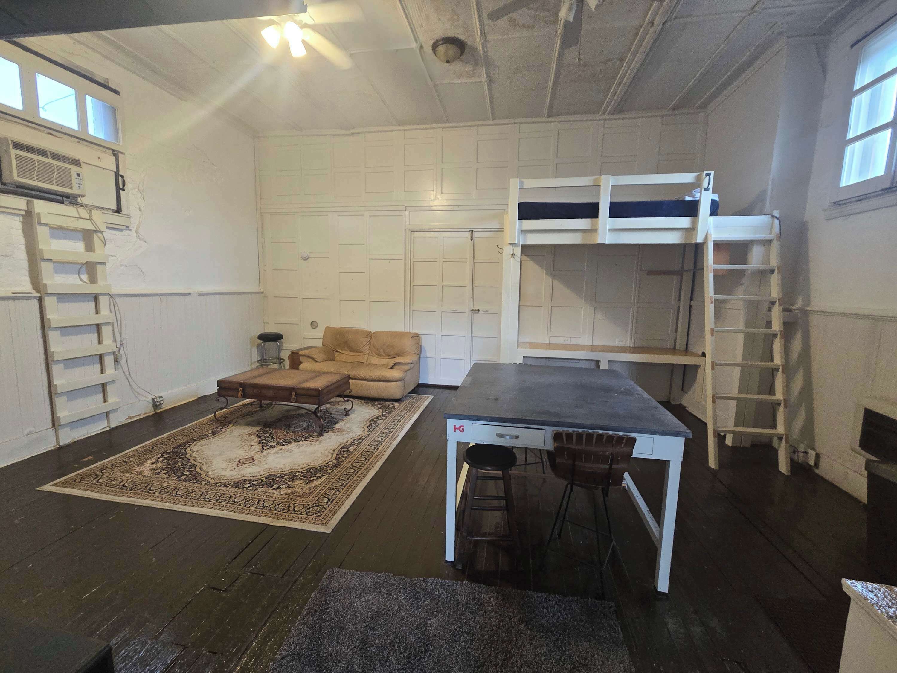 Une pièce comprenant un lit superposé, un canapé, une table et un tapis à motifs.