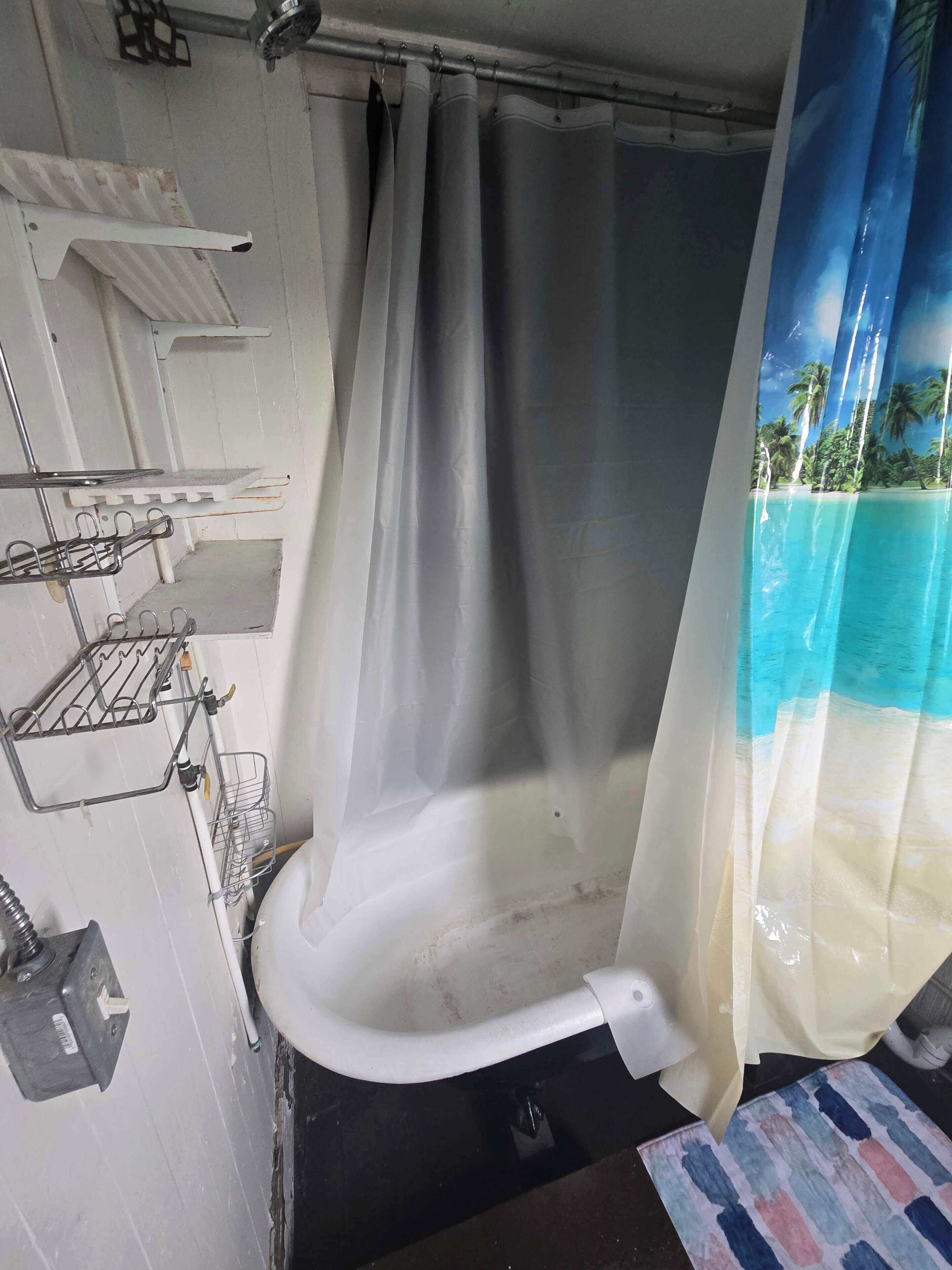 Une salle de bain avec un rideau de douche, un lavabo blanc et un porte-serviettes.