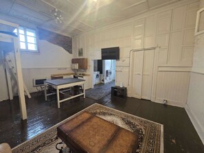 A spacious room with a large table, a sofa, and a patterned rug. - Bunkhouse - Budget Crash Pad - East Carson Street (Pittsburgh)