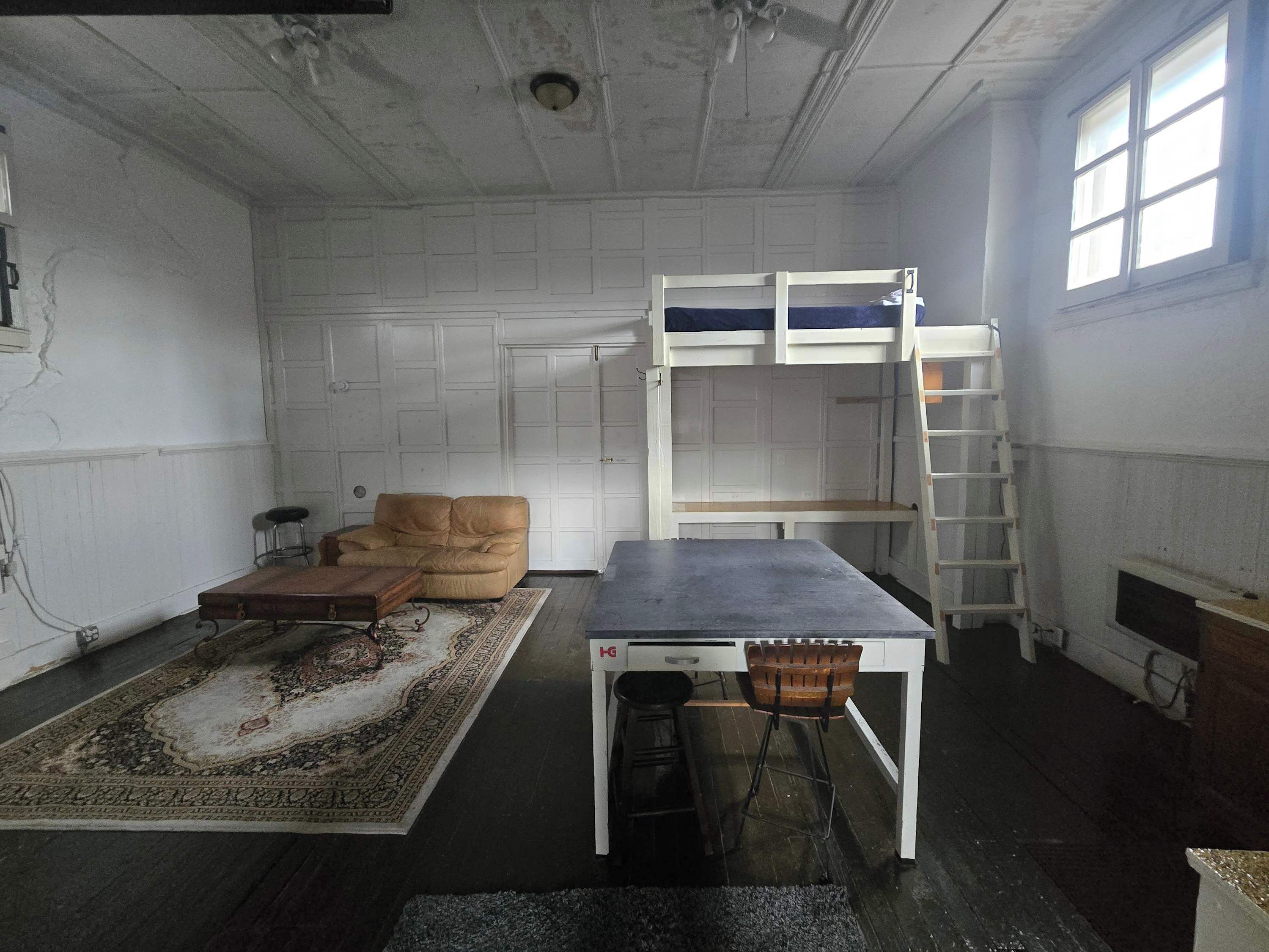 Une pièce comprenant un lit superposé, un canapé, une table et une échelle.