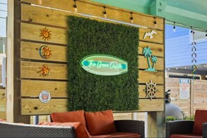 Eine Wand mit einem grünen Kunstgraseinsatz, Holzpaneelen und einem Neonlichtschild mit der Aufschrift 'The Green Casa'.