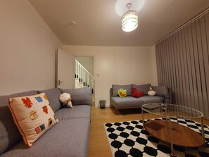 A modern living room with a grey sofa, a glass coffee table, and a patterned rug. - Cosy and very Family-sized with Game and TV rooms and relaxing  & Friendly (London)