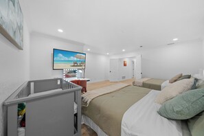 A modern bedroom with a large bed, a TV, and a small desk area.