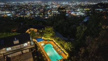 A residential area with a swimming pool surrounded by trees and a building with a balcony.
