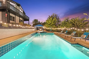 A swimming pool with lounge chairs and a covered seating area, surrounded by a fence and string lights. - Pool, Big Yard, View, King Bed, Parking, 4BR - 2.5Bth (El Cajon)