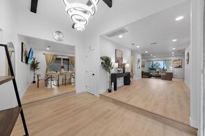 A spacious living area with a wooden floor, a dining area with a table and chairs, and a seating area with a sofa and a coffee table.