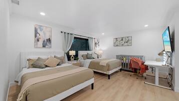 A bedroom with two beds, a desk, a chair, and a TV.