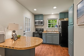 A kitchen with a central island, built-in appliances, and a window with a view of greenery.