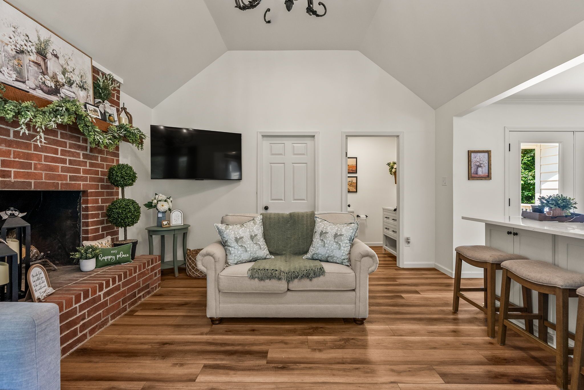 A living room with a fireplace, a sofa, a TV, and a kitchen area.