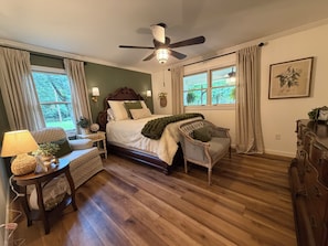 A bedroom with a bed, a chair, a dresser, a nightstand, and a ceiling fan.
